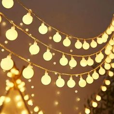 a string of lights hanging from the side of a building in front of a christmas tree