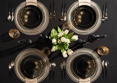 an overhead view of a table setting with flowers on the centerpiece and black plates