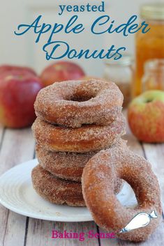 a stack of glazed apple cider donuts on a plate with apples in the background