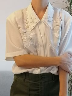 "Vintage white blouse with embroidery. 80's short sleeve shirt with lilac embroidered. Measurements lying flat: Bust: 56 cm / 22\" Length: 70 cm / 27.5\"" Elegant Embroidered Short Sleeve Shirt, Elegant Short Sleeve Embroidered Shirt, Classic Embroidered Summer Shirt, Classic Blouse With Floral Embroidery For Spring, Classic Collared Tops With Floral Embroidery, Classic Collared Top With Floral Embroidery, Classic Embroidered Short Sleeve Top, Classic Embroidered Short Sleeve Shirt, Retro Short Sleeve Top With Floral Embroidery