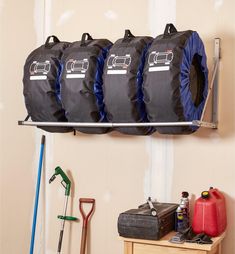 there are four bags hanging on the wall with some tools in front of them,