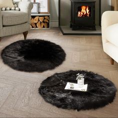 two round black sheepskin rugs on the floor in front of a fire place