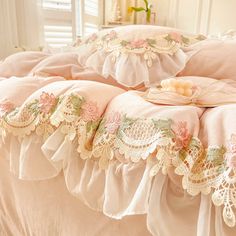 two pink bedspreads with lace trim around the edges and flowers on them, sitting next to each other