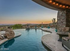 an outdoor swimming pool with lounge chairs and lights