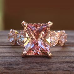 a pink diamond ring sitting on top of a wooden table