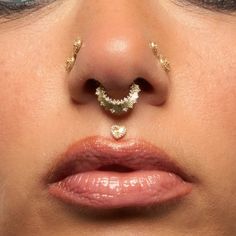 a woman's nose with gold piercings on top of her nose and the bottom part of her nose