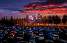 a parking lot filled with lots of cars under a colorful sky at sunset or dawn