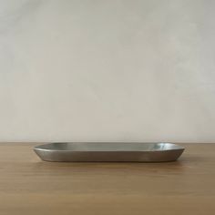 a silver plate sitting on top of a wooden table next to a white wall in the background