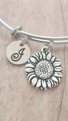 "This listing is for a hand stamped initial bangle featuring a 7/10\" x 3/5\" pewter sunflower charm & 2/5\" stainless steel initial pendant. The stainless steel bangle measures 65mm (2.5\") in diameter and fits most adult women's wrists. All items are lead & nickel free. Please message me with any questions, thank you! Add an initial to any item: https://www.etsy.com/listing/170461597/add-an-initial?ref=shop_home_active&ga_search_query=Add Add a birthstone to any item: https://www.e Sunflower Bracelet, Sunflower Charm, Sunflower Jewelry, Tyler Tx, Sunflower Pendant, Jewelry Summer, Stainless Steel Bangles, Garden Jewelry, Initial Pendant