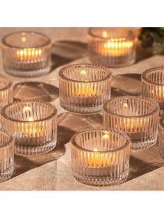 many clear glass candles are lit on the table