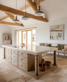 a large kitchen island in the middle of a room with wooden beams on the ceiling