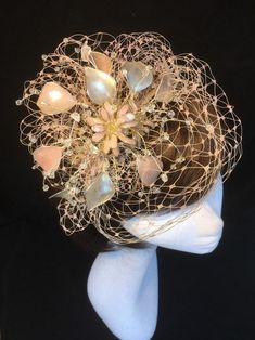 Pale pink, ivory and gold fascinator perfect for the bride or guest who wants something beautifully unique and bespoke. This design is a stunning selection of glass effect leaves and flowers clustered together amongst a fine layer of veiling and set onto a fine comfort tiara band. As with all our designs, this piece can be made exact to the image or in any colour combination to match in with your outfit. If a specific colour is required customers can message over an image of their outfit and acc Handmade Gold Hair Accessories For Wedding, Elegant Pink Fascinator For Gifts, Elegant Pink Fascinator As A Gift, Elegant Pink Fascinator For Gift, Elegant Blush Fascinator For Party, Whimsical Wedding Hat Headpiece, Elegant Pink Fascinator Gift, Wedding Costume Hats And Headpieces With Handmade Flowers, Whimsical Pink Costume Hats And Headpieces For Weddings