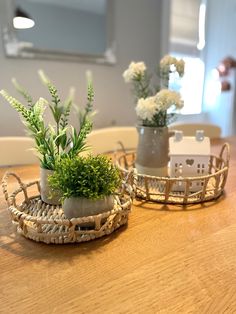 two small baskets with plants in them on a table