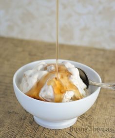 a bowl filled with ice cream and caramel sauce being drizzled over it