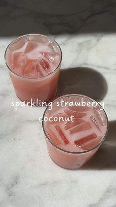 two glasses filled with pink liquid sitting on top of a marble counter next to each other