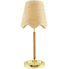 a gold table lamp with a beige shade on the base and a light bulb in the middle