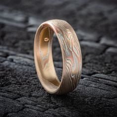 "* Price may vary depending on ring size, please inquire with us directly with your needed size for accurate pricing! This lovely and dainty feeling Mokume Gane band is shown in our Twist Pattern and Fire palette, with a low dome profile and a satin finish. The Fire palette features 14k Red Gold, 14k Yellow Gold, Sterling Silver. Pattern: Twist Palette: Fire Finish: Etched Profile: Low Dome Width Shown: 6mm Size Shown: 8.25 Price does NOT include stones or setting fees. We care about customer se Engraving Option Round Band For Promise Ring, Heirloom Style Polished Wedding Stackable Rings, Polished Wedding Ring Jewelry, Wedding Ring Jewelry With Polished Finish, Adjustable Engraved Promise Bands, Gold Wedding Bands With Engraving Option, Round Polished Finish Jewelry For Wedding, Round Polished Wedding Jewelry, Wedding Band With Engraving Option