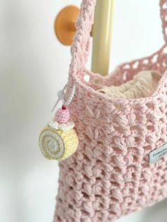 a pink crocheted purse hanging from a hook