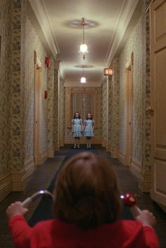 two girls in red shirts are walking down a hallway with mirrors on the wall behind them