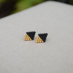 Satin 24kt Gold Plated and Matte Black Glass Seed Beads This beautiful pair of diamond-shaped stud earrings is a lovely way to add simplicity to your wardrobe, or give as a gift. Each earring has 25 Japanese Miyuki Delica beads expertly handwoven together into a minimalist diamond shape by needle and strong nylon thread. Each delicate earring is attached to a 14kt gold filled ear post with matching back. The size of each diamond is 11 mm tall by 8 mm wide. Delicate Earring, Beaded Jewelry Earrings, Stitch Earrings, Bead Loom Designs, Diamond Shape Earrings, Miyuki Delica Beads, Brick Stitch Earrings, Bead Weaving Patterns, Beaded Earrings Patterns