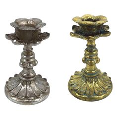 two metal candlesticks sitting next to each other