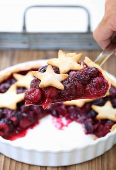 someone is holding up a piece of pie with cherry toppings and star shaped cookies on top