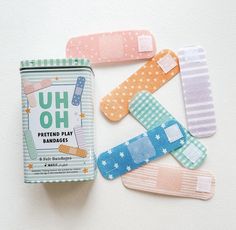 four different colored hair clips sitting on top of a white table next to a can