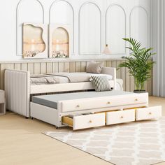 a white daybed with drawers underneath it in a living room next to a couch