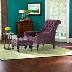 a living room with green walls and purple chair in the corner, side table next to it