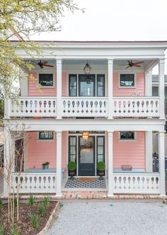 a pink house with white balconies and black shutters on the second story