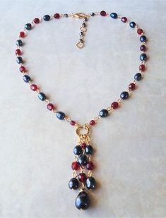 "You really can't go wrong with this classic necklace. It is so elegant and versatile, perfect for all seasons. This lariat style necklace combines luminous baroque black pearl with red garnet crystals. It features a decorative infinity circle plated in 24 karat gold. This necklace measures 16\" in length, with 2 inches extension. The pendant-tassel measures 2\" in length. This stunning necklace is unique, feminine and eye-catching, Perfect for anyone that wants to make a statement or to wear to Elegant Lariat Jewelry With Dangling Beads, Elegant Beaded Dangle Necklaces With Lobster Clasp, Elegant Beaded Dangle Necklace With Lobster Clasp, Elegant Dangle Beaded Necklaces With Faceted Beads, Elegant Dangle Beaded Necklace With Faceted Beads, Elegant Wire Wrapped Dangle Beaded Necklaces, Elegant Lariat Necklace With Dangling Beads, Elegant Faceted Beads Drop Necklace For Gift, Elegant Red Lariat Necklaces