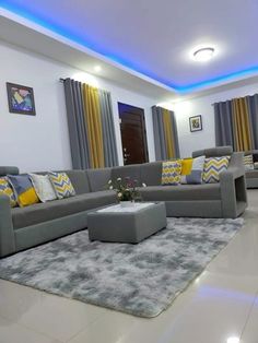 a living room with grey couches and yellow pillows on top of the sofas