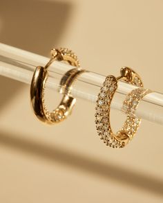 two pairs of diamond hoop earrings sitting on top of each other