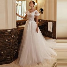 a woman standing in front of a mirror wearing a wedding dress with ruffle sleeves