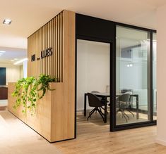 an office with wooden paneling and plants on the wall, along with glass doors