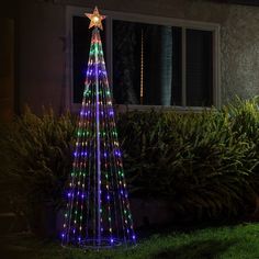 a lighted christmas tree in front of a house