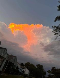 an orange cloud is in the sky above some houses