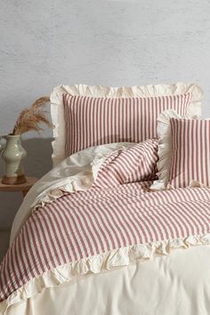 red and white striped bedding with ruffles on the bottom, along with pillows