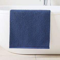 a blue bath mat sitting on top of a white bath tub next to a faucet