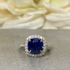 a blue sapphire and diamond ring with white flowers in the background