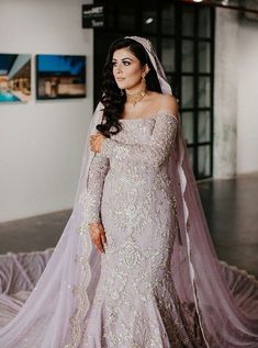 a woman in a wedding dress posing for the camera with her veil draped over her head