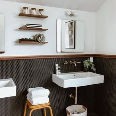 a white sink sitting under a bathroom mirror next to a wooden stool with two towels on it