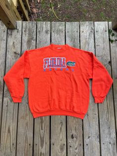 "Show your love for the Florida Gators with this vintage Champion University of Florida Gators Orange Crewneck Sweatshirt. This sweatshirt is made from high-quality materials and features the Gators team logo prominently on the front. Perfect for football season and any Gators fan, this sweatshirt comes in size XL and is made by Tultex. perfect for both men and women. It is also perfect for regular season games and is a must-have for any sports fan. This item is made in Mexico and is perfect for Oversized Long Sleeve Throwback Tops, 90s Crew Neck College Sweater, 90s Style Long Sleeve Sweatshirt Fan Merchandise, Vintage Fan Gear Tops With Crew Neck, Vintage Crew Neck Tops For Fan Gear, Retro Long Sleeve Sweatshirt For Fan Gear, Retro Long Sleeve Sweatshirt For Fans, Retro Crew Neck Sweatshirt For Fan Merchandise, Retro Fan Gear Sweatshirt For Fall