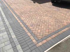 a black car parked on the side of a brick road next to a parking meter