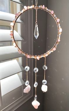 a circular wind chime with pink and white stones hanging from it's side