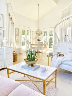 a living room filled with white furniture and lots of flowers on top of a coffee table