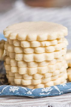 a stack of shortbread cookies sitting on top of a blue and white cloth next to a bowl