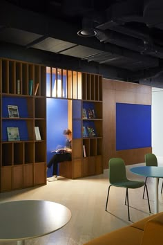 a person sitting at a table in front of a book shelf with books on it