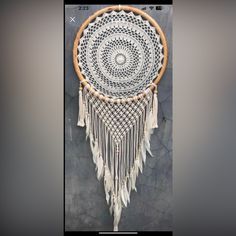 a white and brown dream catcher hanging on a wall next to a black stone wall