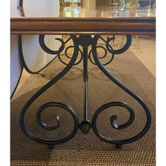 an iron table with glass top in the middle of a carpeted flooring area